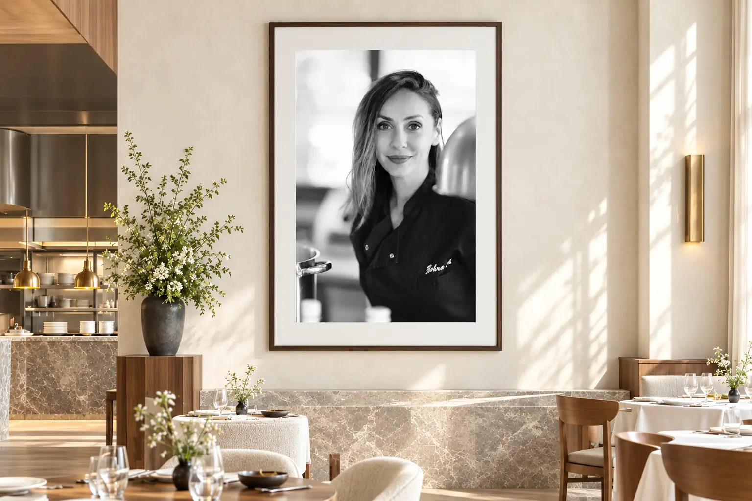 Ingelijst zwart-witportret van chef-kok Zohra aan een lichte restaurantmuur